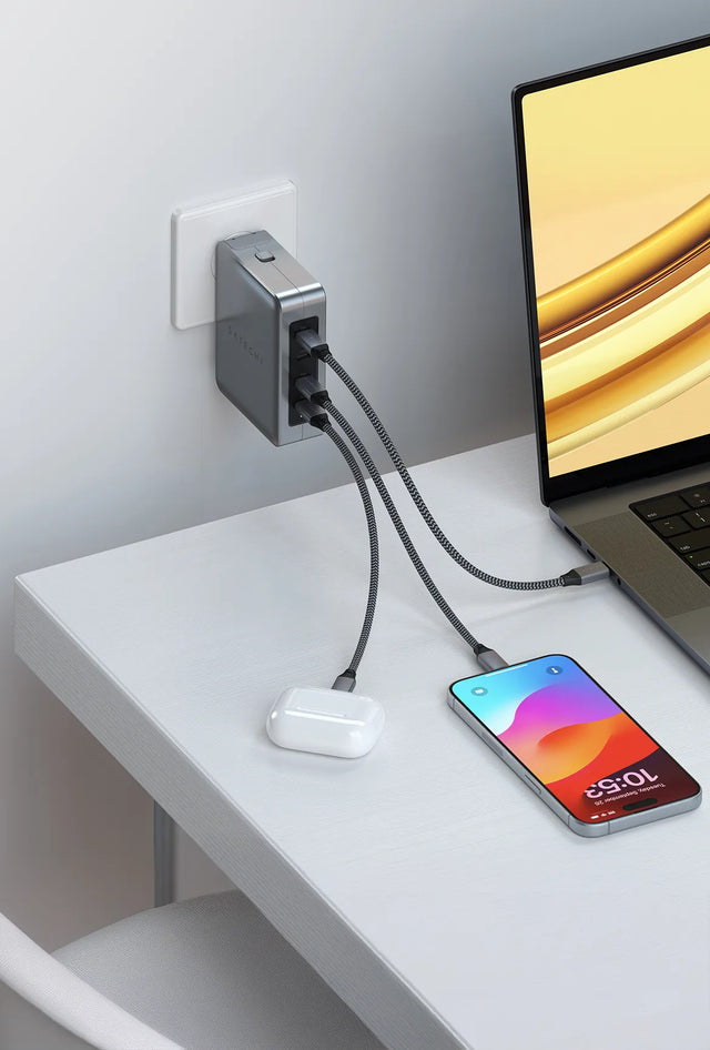 Satechi 145W Travel Charger plugged into a wall outlet, charging a MacBook, an iPhone and an AirPods case at once with three braided USB-C cables.