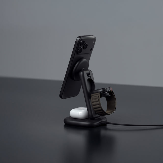 Satechi 3-in-1 25W wireless charging stand charging an iPhone, Apple Watch and AirPods on a dark surface.