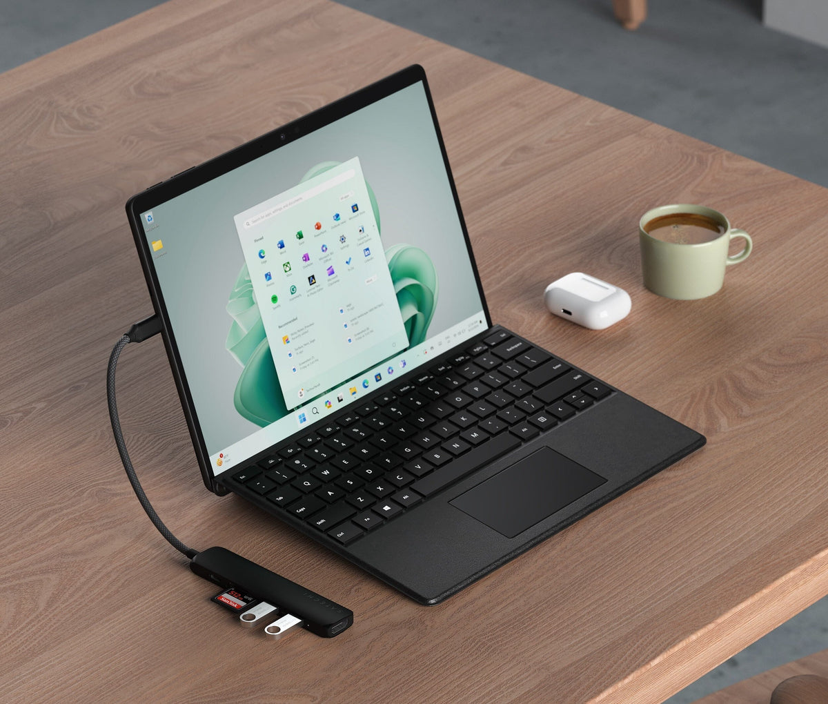 6-in-1 USB-C Slim Multiport Adapter in Black connected to a Surface tablet with keyboard on a wooden table