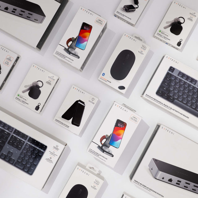 Assortment of Satechi product boxes on a white surface: 3-in-1 Foldable Qi2 Wireless Charging Stand, Mini NVMe SSD Enclosure, Findall Keychain, OnTheGo Mouse, SM3 Slim Mechanical Backlit Bluetooth Keyboard, Magnetic Wallet Stand and Triple 4K Display Docking Station.