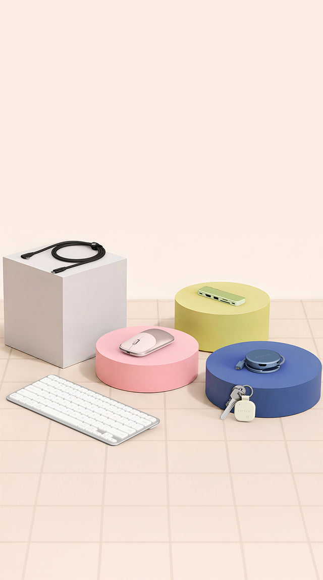 Satechi accessories, USB-C Snap Hub, OntheGo 5-in-1 Multiport adapter, Ex Mouse, and EX1 Keyboard on pastel display blocks. Leaning against block is a sand FindAll keychain tracker on keys.