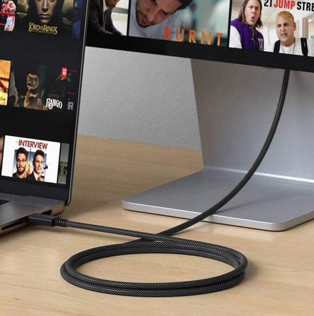 Satechi braided USB-C cable connecting a laptop to an external monitor on a wooden desk.