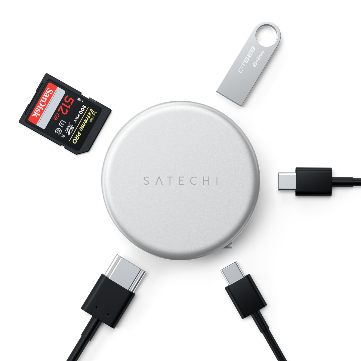 A silver OntheGo™ 5-in-1 Multiport Adapter is shown in a flat-lay arrangement with various accessories on a white background, including a SanDisk 128GB SD card, a silver USB flash drive, and four black USB-C to USB-C cables.
