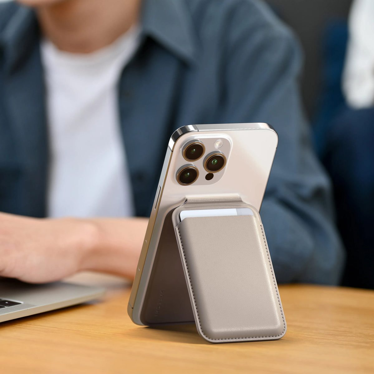Vegan-Leather Magnetic Wallet Stand in Taupe propping up an iPhone next to a laptop