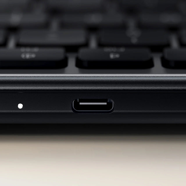 Close-up of the USB-C charging port and LED indicator on the edge of the Satechi Slim EX1 Wireless Keyboard in dark gray.