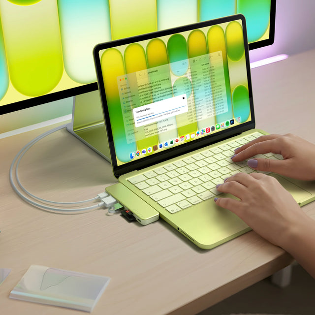 A Citrus MacBook Neo with a matching Satechi USB-C Snap Hub in Citrus attached and displaying onto second external iMac monitor.