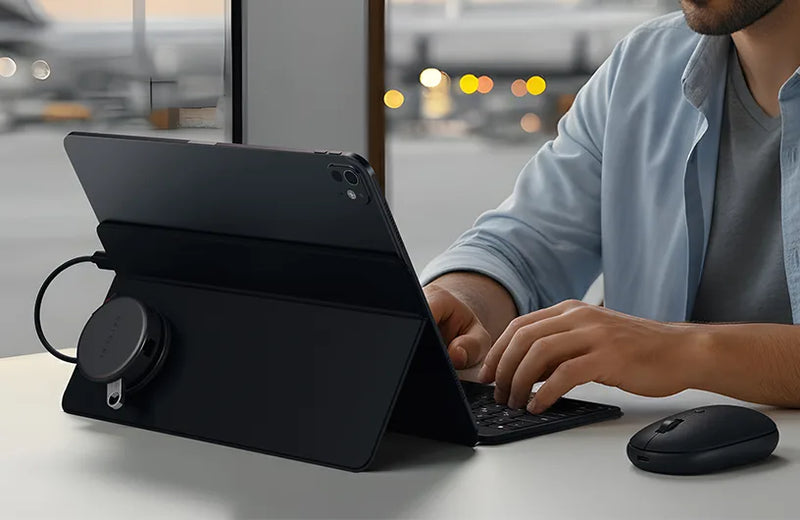 Person using a black tablet with a keyboard stand and mouse on a desk.