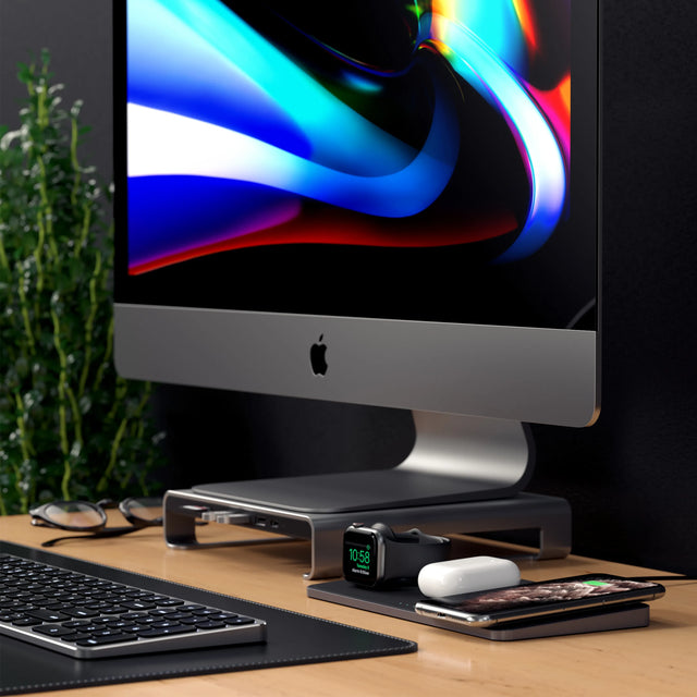 Satechi Trio Wireless Charging Pad charging an Apple Watch, AirPods and an iPhone in front of an iMac on a monitor stand.