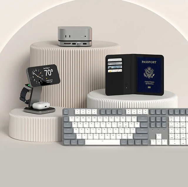 Satechi best sellers on pedestals: a Mac mini stand and hub, a 3-in-1 charging stand holding an iPhone, Apple Watch and AirPods, a passport wallet, and a full-size gray and white keyboard.