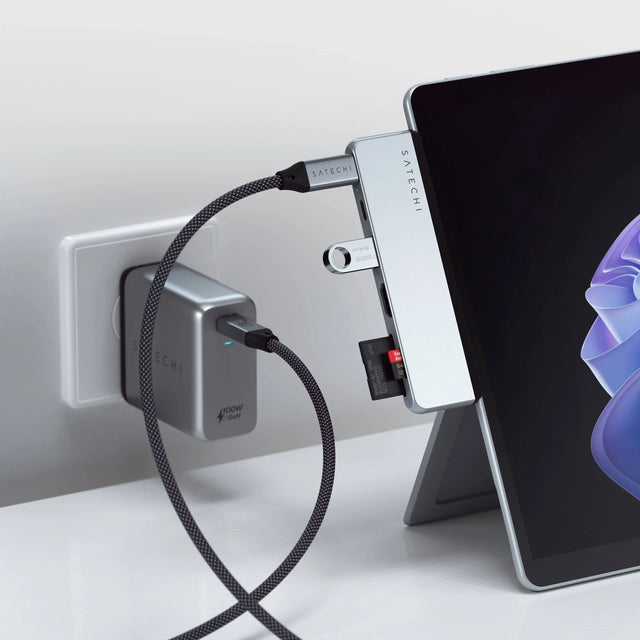 Satechi Dual USB-C Hub attached to a Surface Pro 9 with a USB flash drive and SD card inserted, powered by a Satechi 100W GaN wall charger.