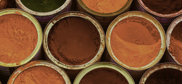 Top down view of buckets of soy ink laid out in varying colors of orange.