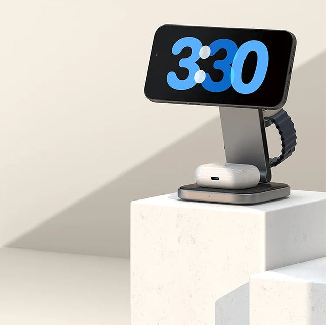 Satechi 3-in-1 Foldable Qi2 Wireless Charging Stand charging an iPhone in StandBy mode showing 3:30, plus an Apple Watch and AirPods case. Alongside is a desktop charger and Duo Wireless Charger Power Stand.