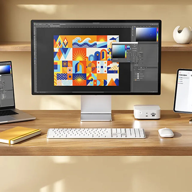 White Satechi keyboard and mouse on a wooden desk in front of a monitor, with a laptop, iPad, notebook and a small white hub beside the monitor.