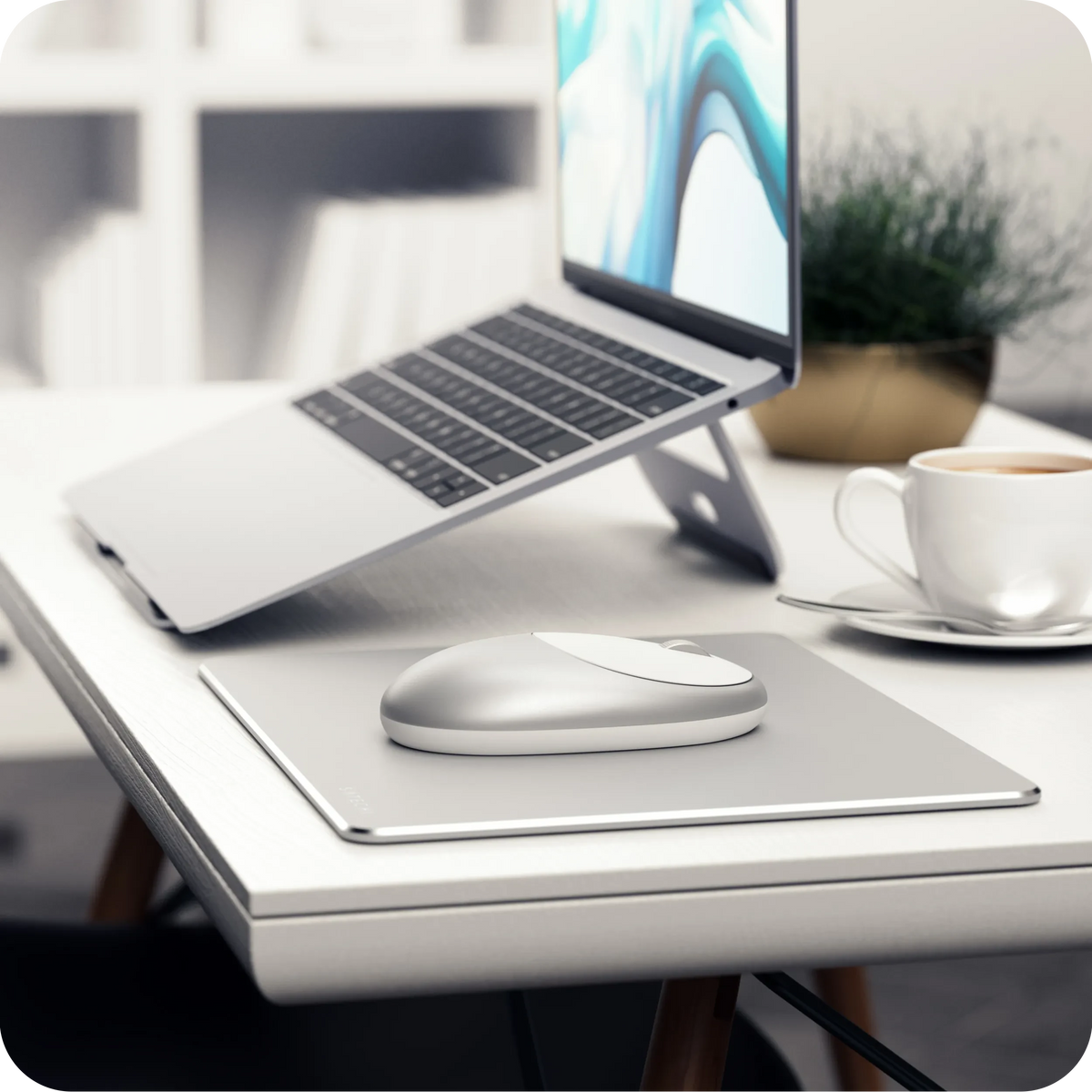 M1 Bluetooth Mouse in Silver on a desk under a laptop on a stand