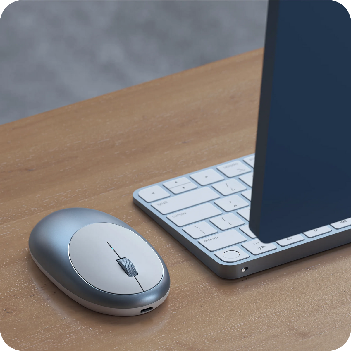 M1 Bluetooth Mouse in Blue next to a keyboard on a wooden desk