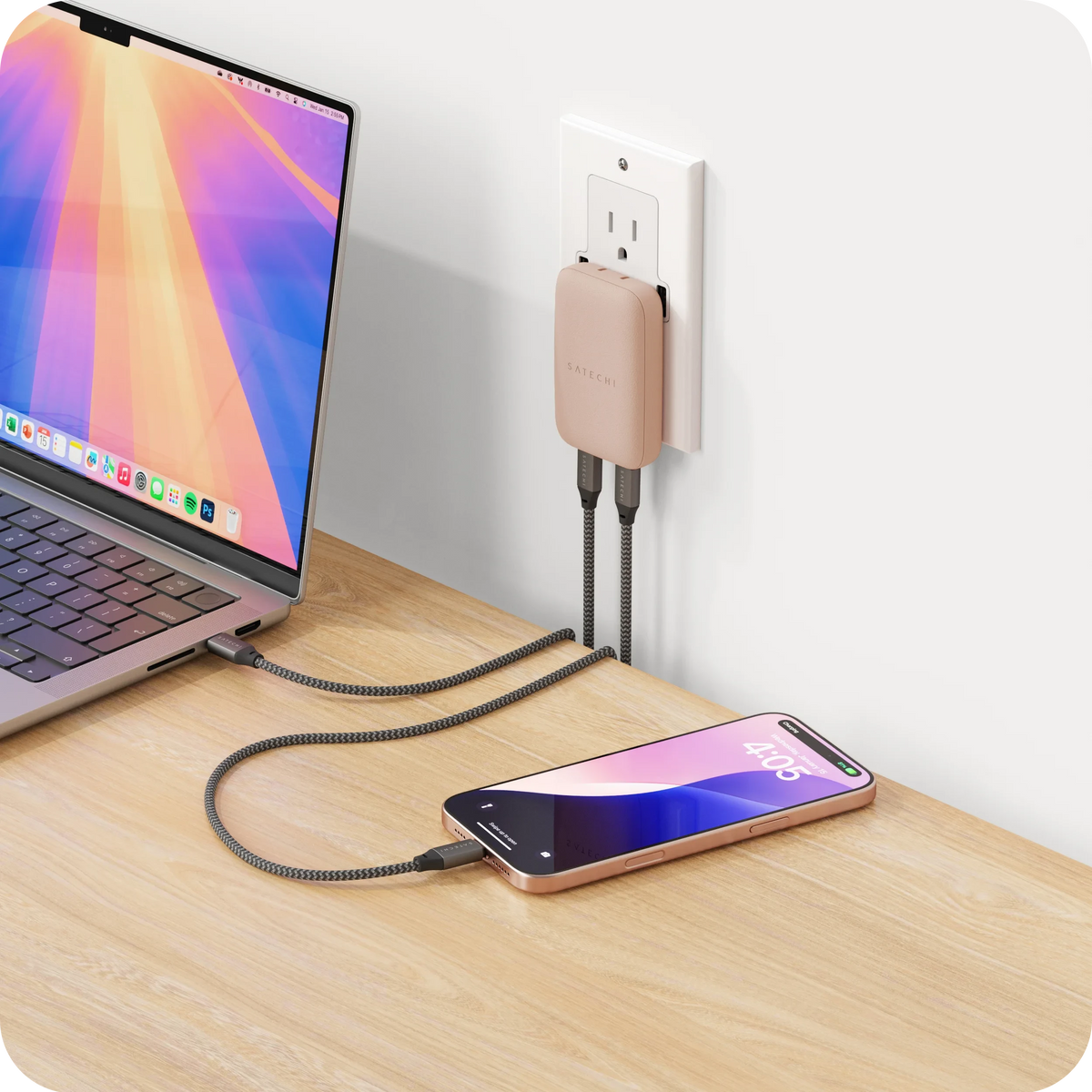 OntheGo 67W Slim Wall Charger in Desert Rose plugged into a wall outlet, charging a laptop and an iPhone