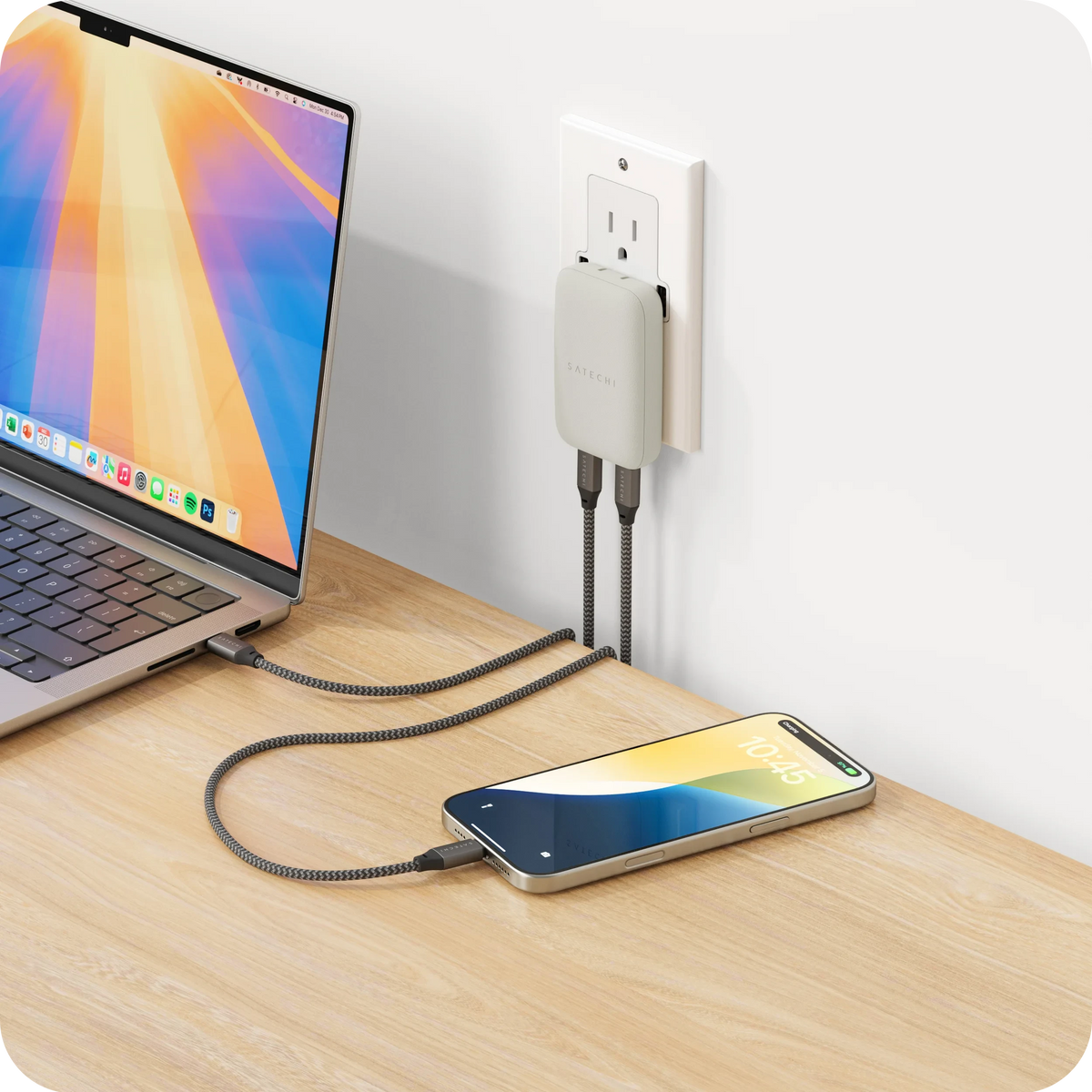 OntheGo 67W Slim Wall Charger in Sand plugged into a wall outlet, charging a laptop and an iPhone
