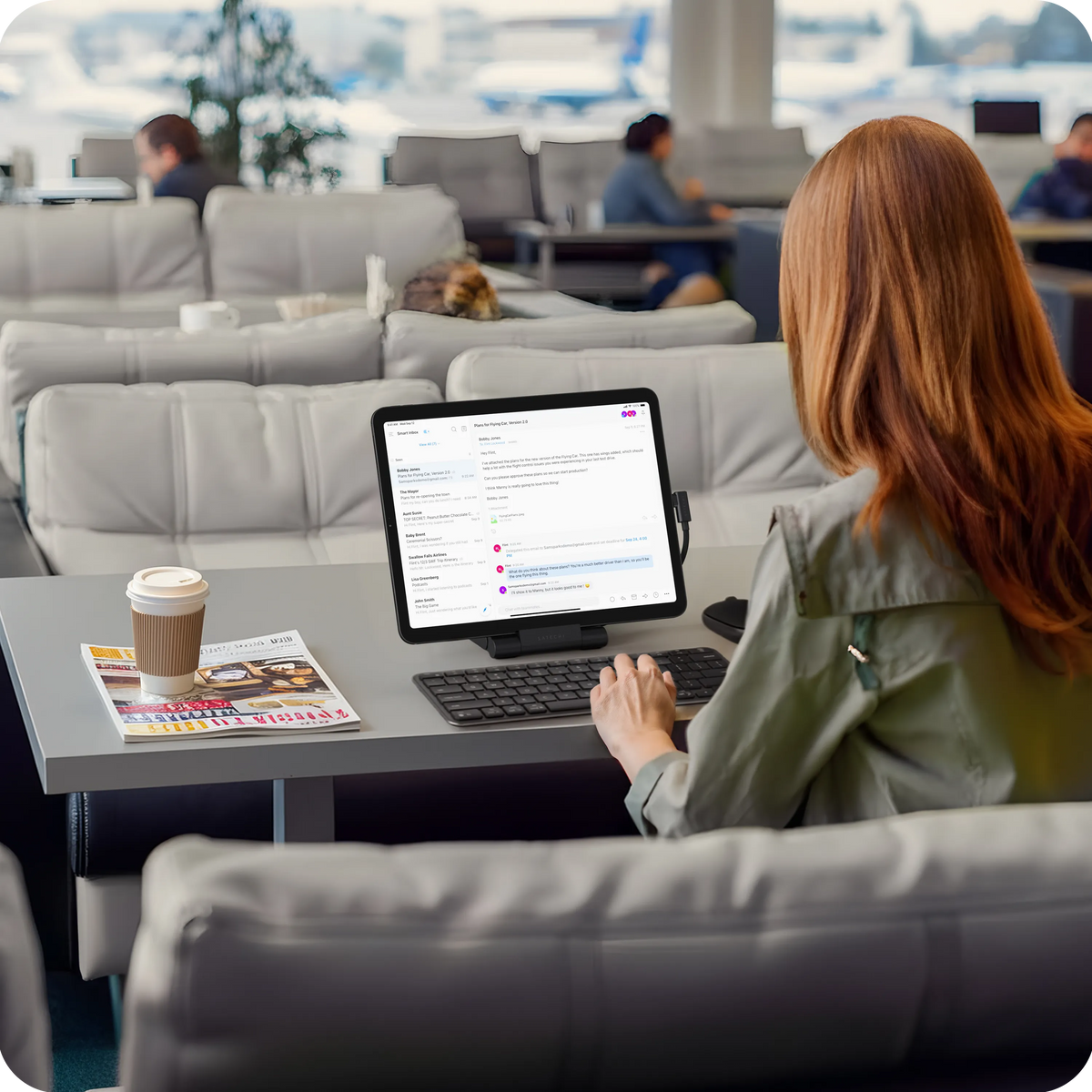 Woman using an iPad on the OntheGo Foldable Stand Hub at an airport lounge table