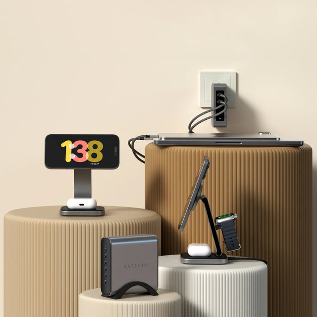 Assortment of Satechi charging products ( 3-in-1 Foldable Qi2 Wireless Charging Stand, 2-in-1 Foldable Qi2 Wireless Charging Stand, 145W USB-C 4-Port GaN Travel Charger, 200W USB-C 6-Port GaN Charger) displayed on neutral pedestals, including iPhone, Apple Watch, AirPods, and MacBook.