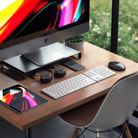 Desk setup with a Satechi aluminum monitor stand under an iMac, plus a Satechi wireless keyboard, wireless mouse, and Trio Wireless Charger With Magnetic Pad.