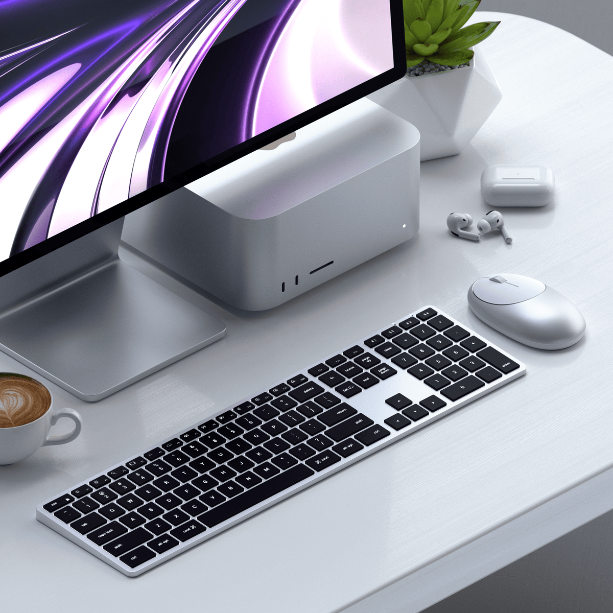 Slim X3 Bluetooth Backlit Keyboard in Silver on a white desk with a Mac Studio, monitor, mouse, AirPods and coffee