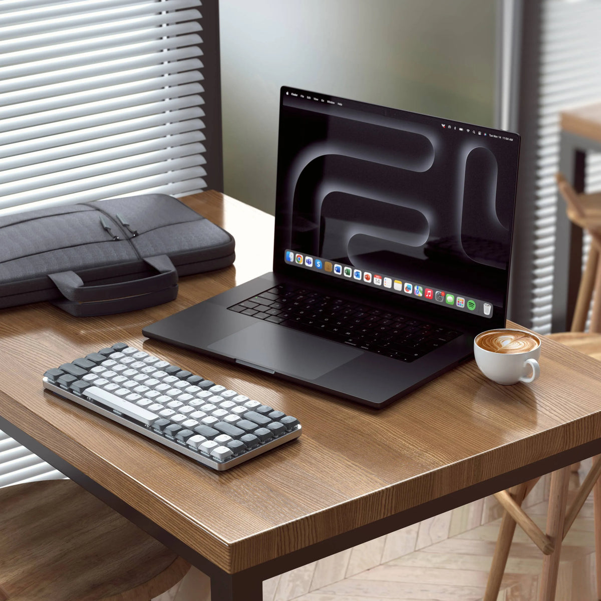 Satechi SM1 Slim Mechanical Backlit Bluetooth Keyboard on a wooden table next to a MacBook Pro, laptop bag and coffee.