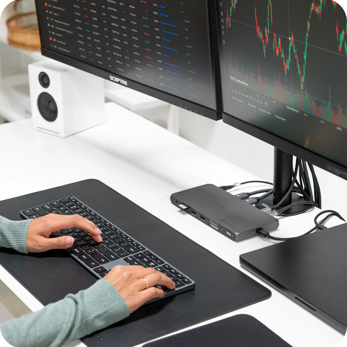 Thunderbolt 4 Docking Station with DisplayLink on a desk under two monitors, with a person typing on a keyboard
