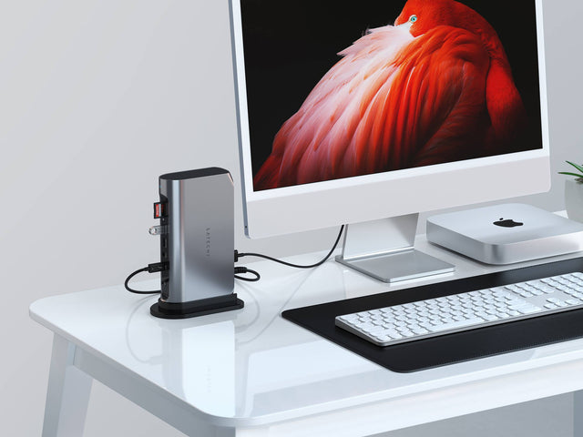 Satechi Thunderbolt 4 Multimedia Pro Dock standing upright on a white desk, connected to an iMac and Mac mini, with a white keyboard on a black desk mat.