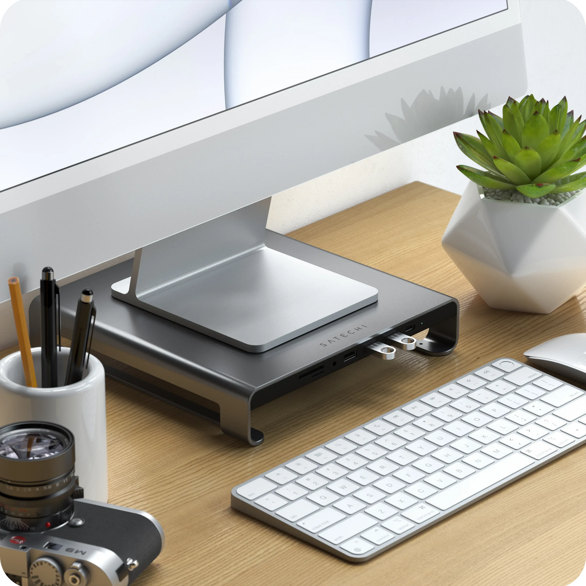 Type-C Aluminum Monitor Stand Hub for iMac in Space Gray on a wooden desk with a keyboard and camera, close up