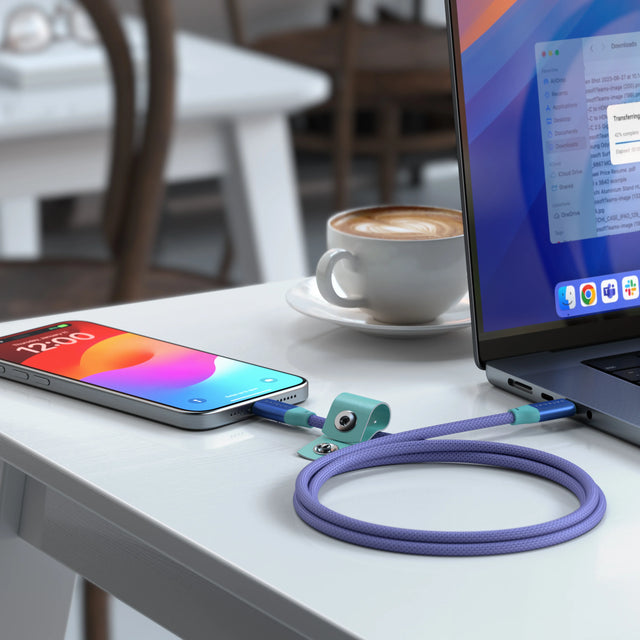 Satechi USB-C to USB-C Data and Charge Cable in Purple Aquatic Awe connecting an iPhone to a laptop on a cafe table, with a teal cable strap.