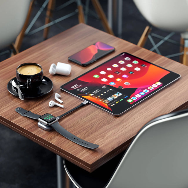 Satechi USB-C Magnetic Charging Dock plugged into an iPad Pro, charging an Apple Watch on a wooden table.