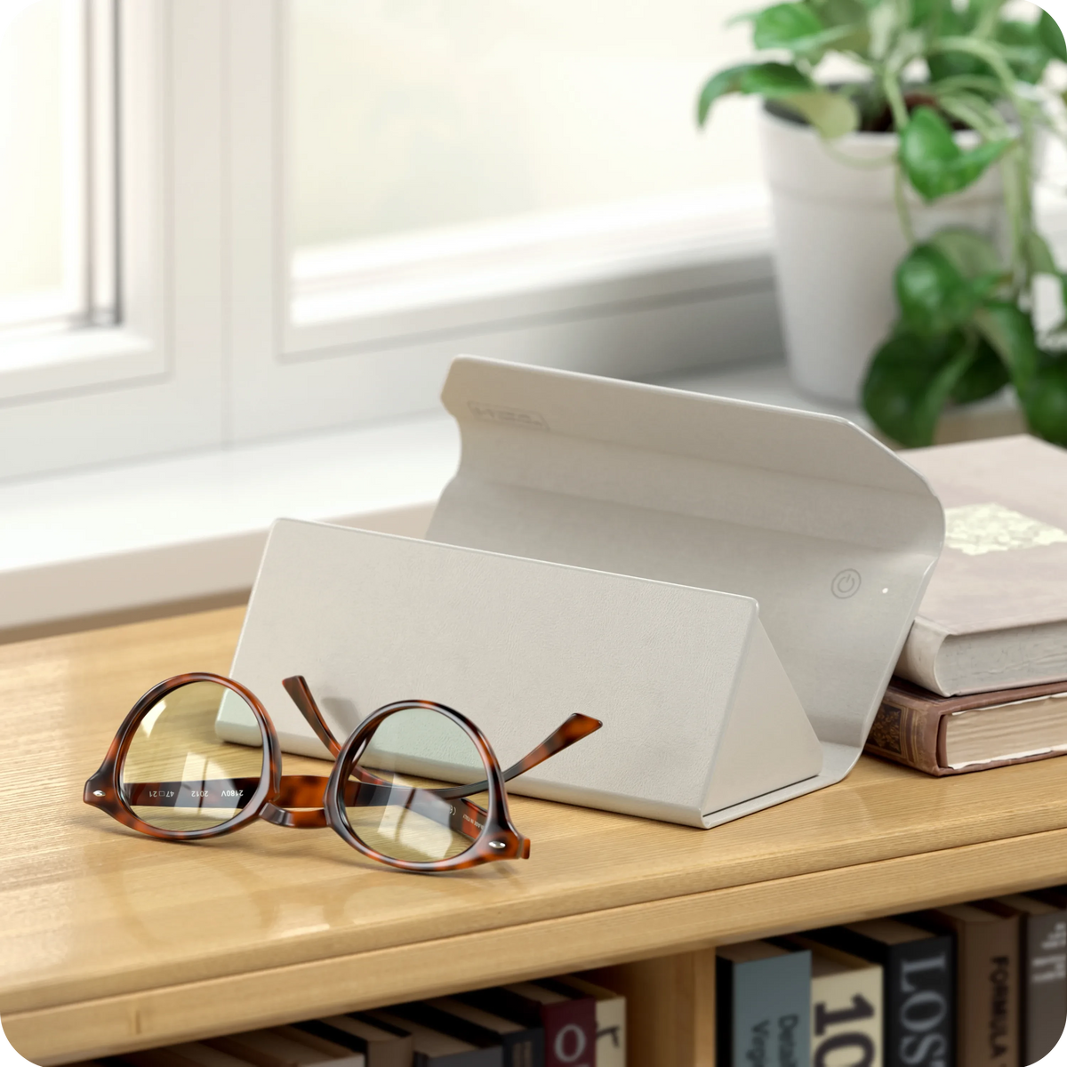 Vegan-Leather FindAll Glasses Case in Sand on a shelf with eyeglasses and books