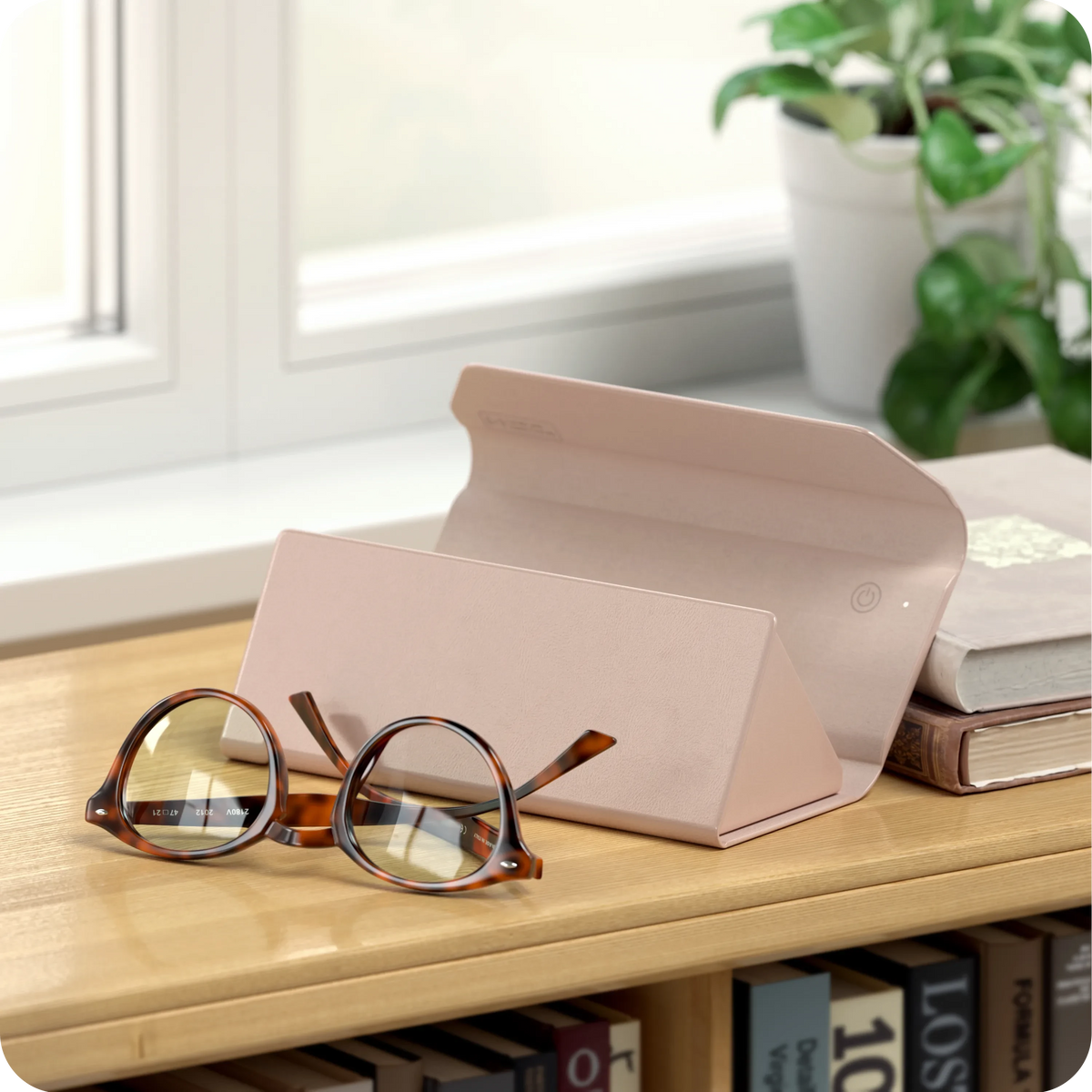 Vegan-Leather FindAll Glasses Case in Desert Rose on a shelf with eyeglasses and books