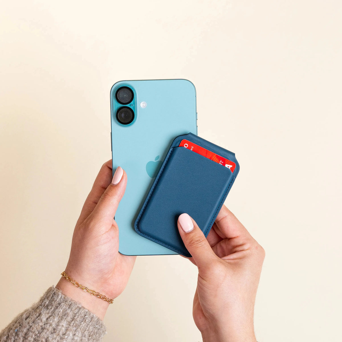 Hands attaching the Vegan-Leather Magnetic Wallet Stand in Dark Blue to the back of an iPhone