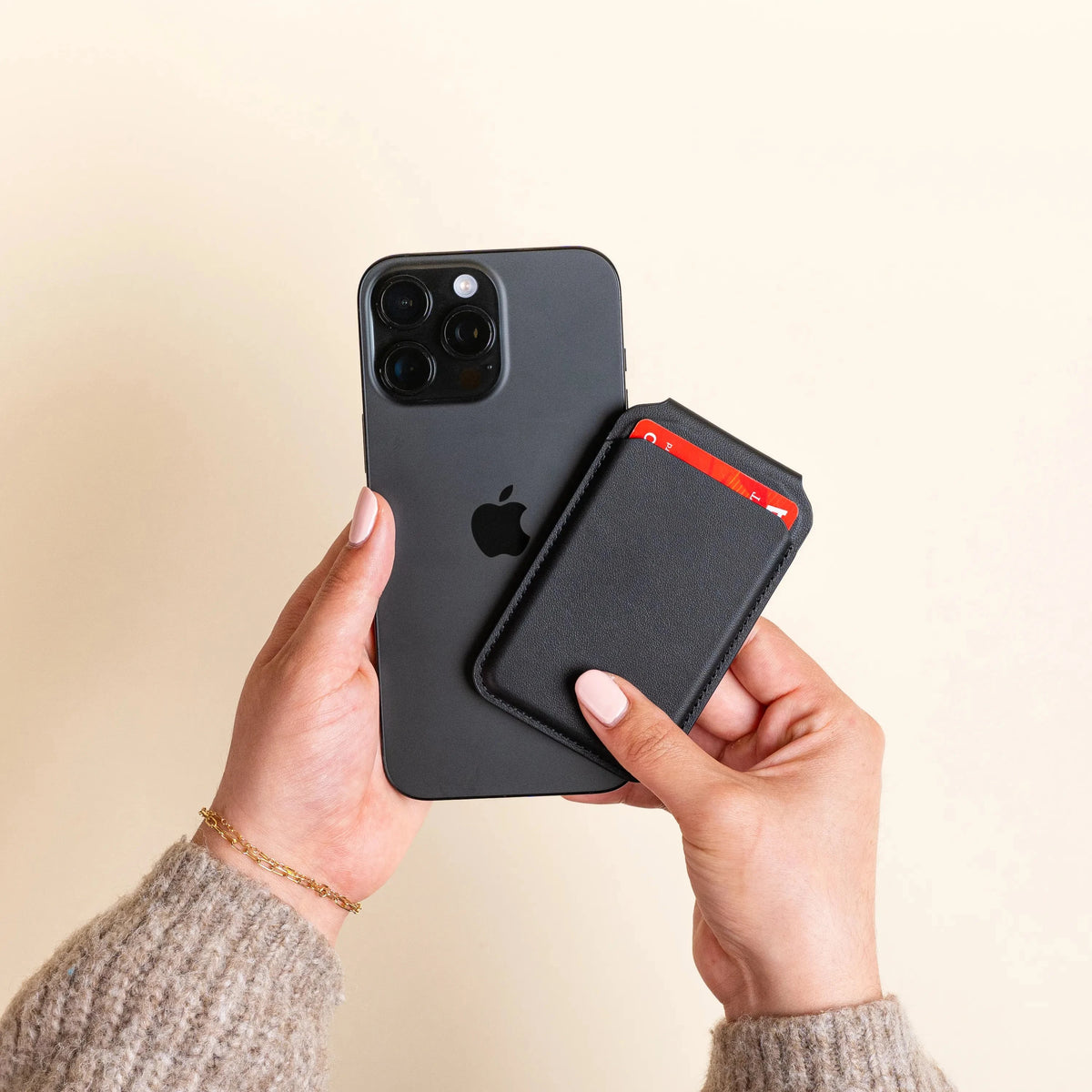 Hands attaching the Vegan-Leather Magnetic Wallet Stand in Black to the back of an iPhone