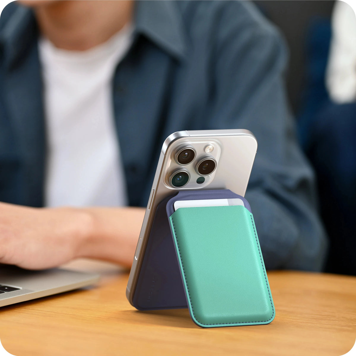 Vegan-Leather Magnetic Wallet Stand in Aqua and Purple propping up an iPhone next to a laptop