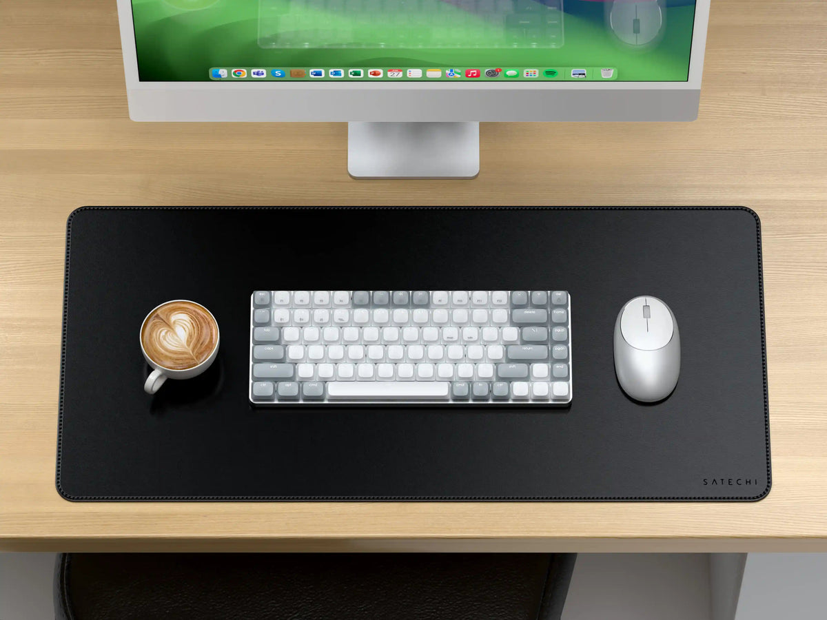 Vegan-Leather Premium Desk Mat in Black on a wooden desk under an iMac, with a keyboard, mouse and coffee