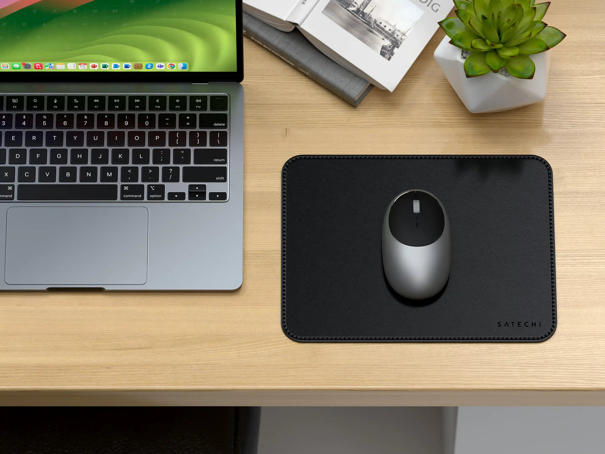 Vegan-Leather Premium Mouse Pad in Black with a mouse on a wooden desk next to a laptop