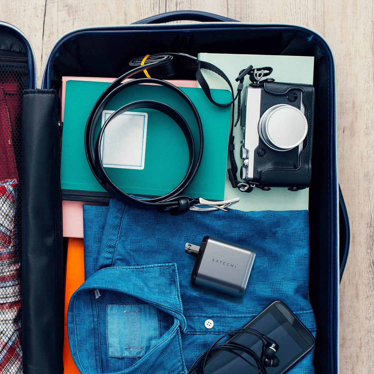 30W Dual-Port Wall Charger packed in a suitcase with clothes, a camera and cables