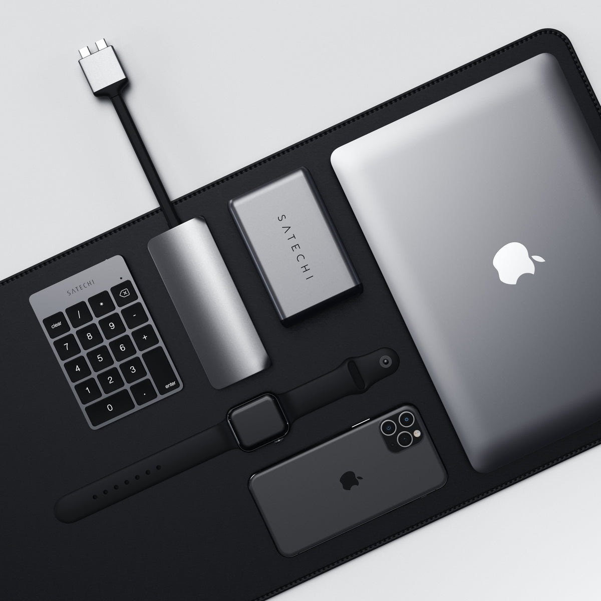 Aluminum Slim Rechargeable Bluetooth Keypad in Space Gray on a dark desk mat with a laptop, hub, phone and Apple Watch