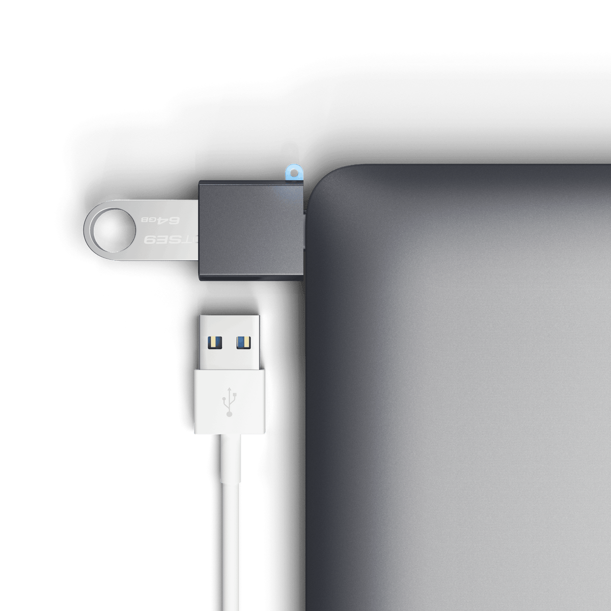 Aluminum USB-C to USB-A 3.0 Adapter in Space Gray plugged into a laptop with a flash drive and USB cable, close up