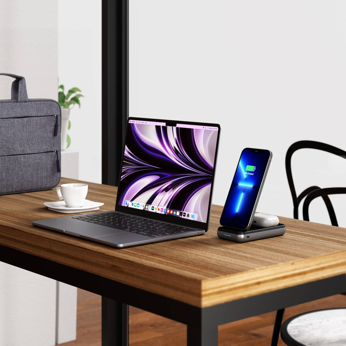 Duo Wireless Charger Power Stand charging an iPhone on a wooden cafe table next to a MacBook