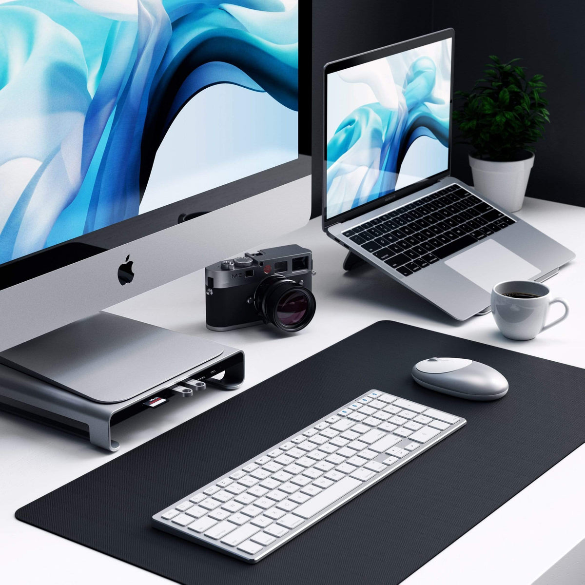 Type-C Aluminum Monitor Stand Hub for iMac in Space Gray under an iMac on a desk with a MacBook on a stand and a desk mat