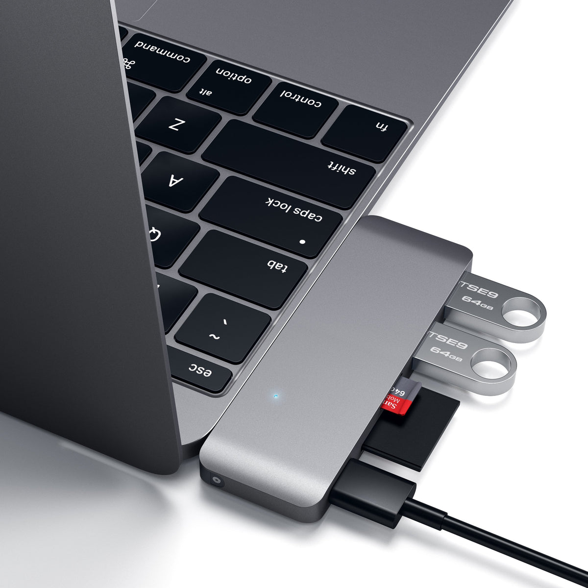 Type-C Pass-Through USB Hub in Space Gray plugged into a MacBook with flash drives and an SD card, close up