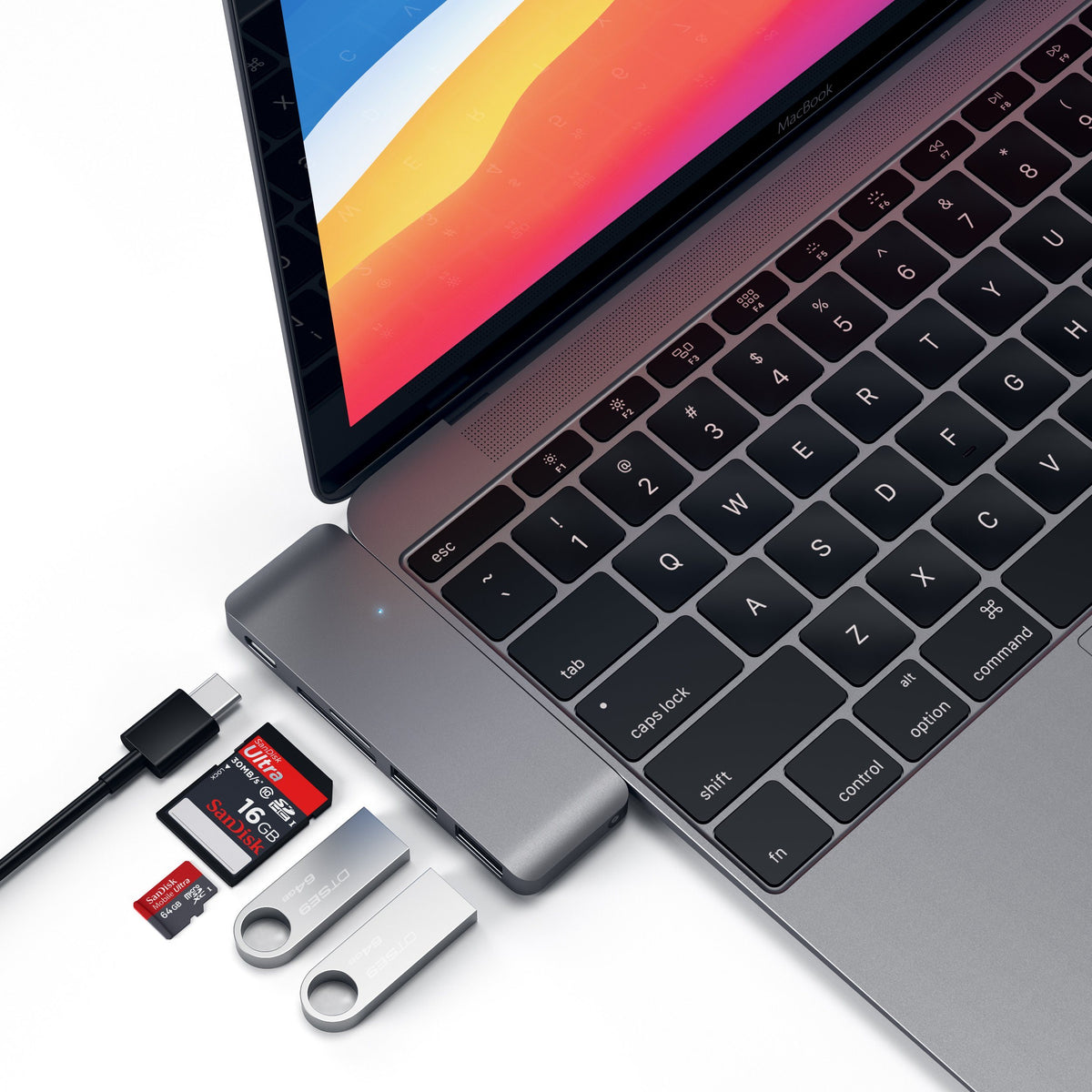 Type-C Pass-Through USB Hub in Space Gray plugged into a MacBook with a cable, SD card and flash drives