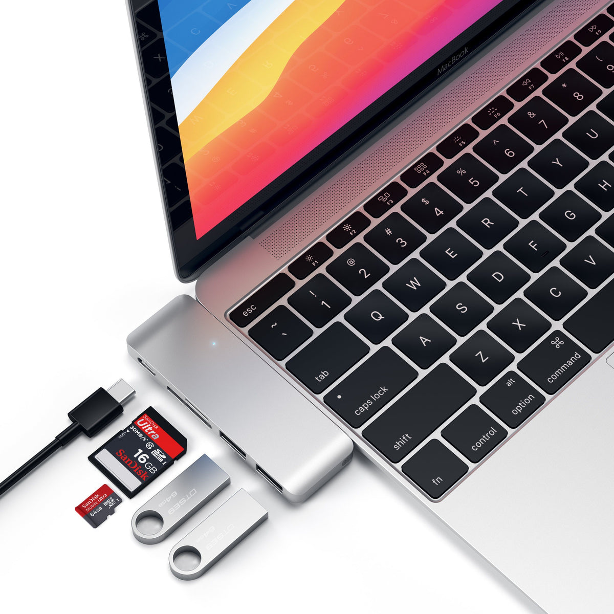 Type-C Pass-Through USB Hub in Silver plugged into a MacBook with a cable, SD card and flash drives