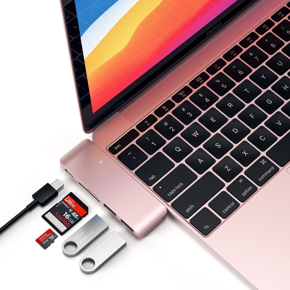 Type-C Pass-Through USB Hub in Rose Gold plugged into a MacBook with a cable, SD card and flash drives