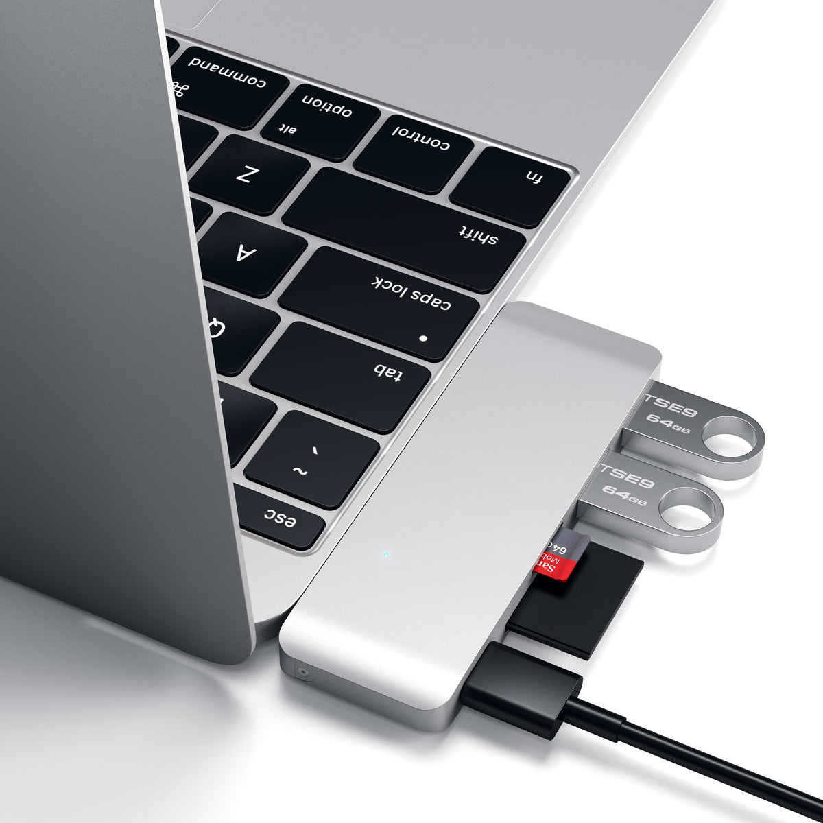 Type-C Pass-Through USB Hub in Silver plugged into a MacBook with flash drives and an SD card, close up