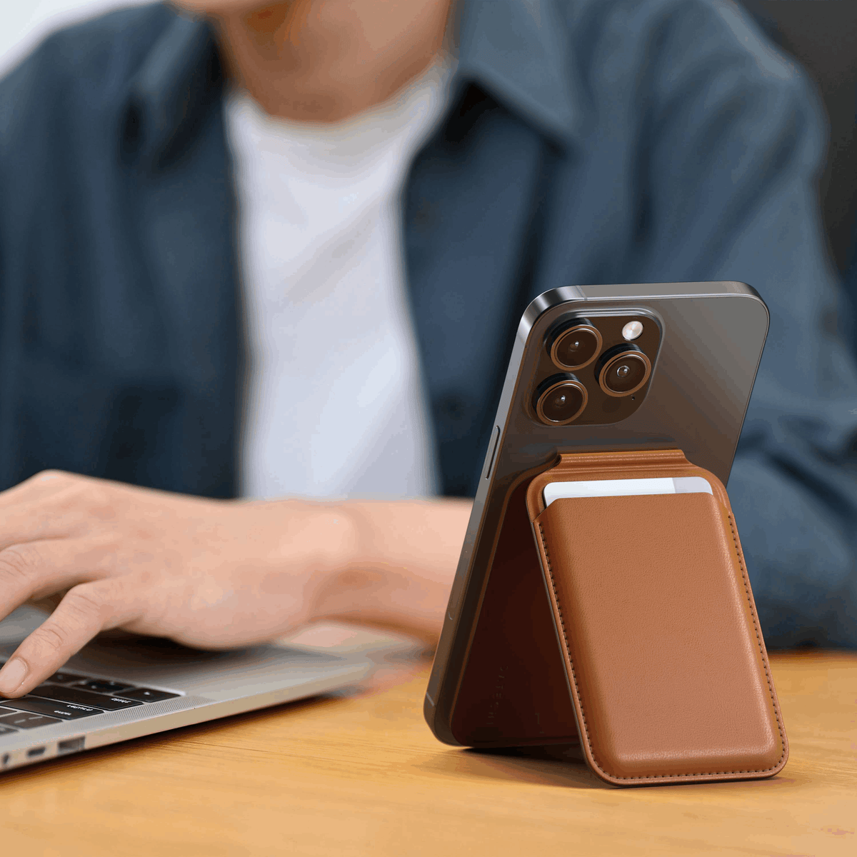 Vegan-Leather Magnetic Wallet Stand in Brown propping up an iPhone next to a laptop