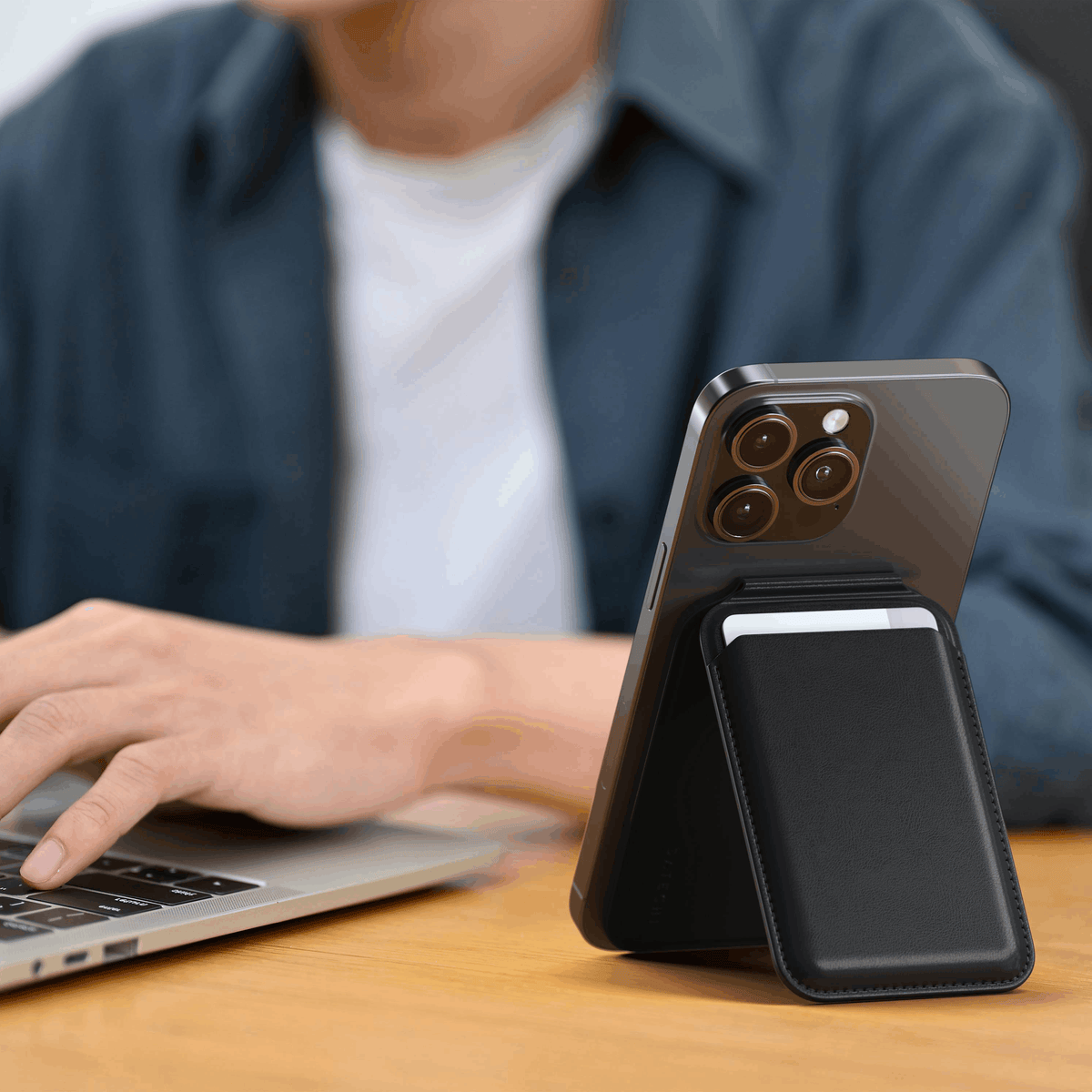 Vegan-Leather Magnetic Wallet Stand in Black propping up an iPhone next to a laptop